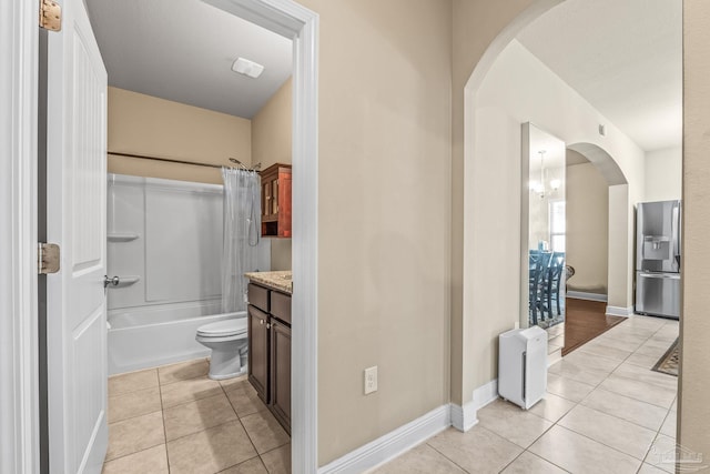 full bathroom with toilet, an inviting chandelier, vanity, shower / bath combo with shower curtain, and tile patterned flooring