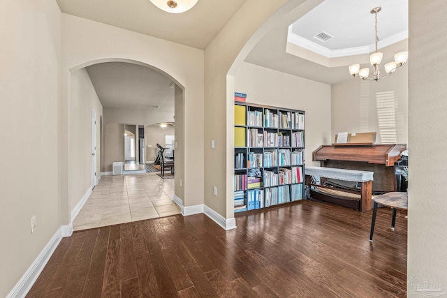 interior space featuring an inviting chandelier, wood-type flooring, and a raised ceiling