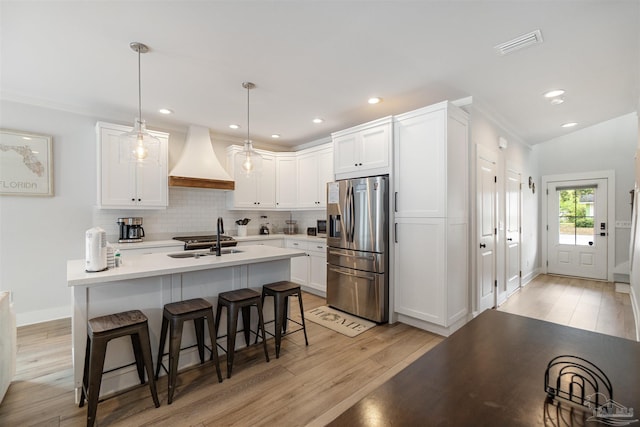2550 N 11th Ave, Pensacola, FL 32503 - kitchen with stainless steel fridge with ice dispenser, a sink, light wood-style floors, custom range hood, and a kitchen bar