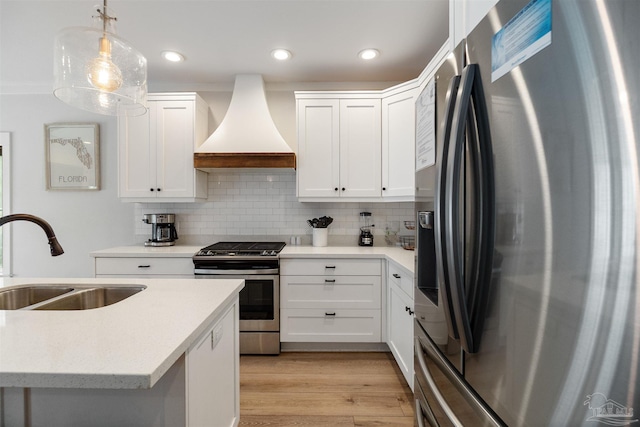 2550 N 11th Ave, Pensacola, FL 32503 - kitchen with appliances with stainless steel finishes, custom range hood, a sink, light wood-style flooring, and backsplash