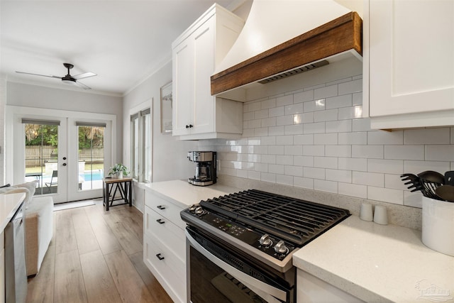 2550 N 11th Ave, Pensacola, FL 32503 - kitchen with gas stove, wall chimney range hood, french doors, white cabinets, and ornamental molding