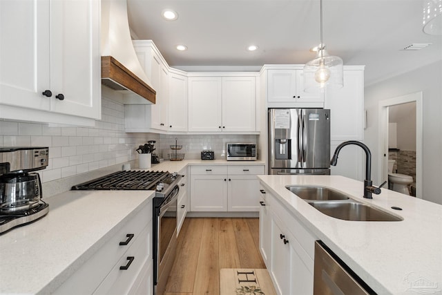 2550 N 11th Ave, Pensacola, FL 32503 - kitchen featuring appliances with stainless steel finishes, custom exhaust hood, a sink, light wood-type flooring, and tasteful backsplash
