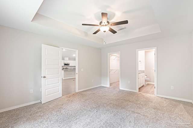 7929 Huntington Creek Ln, Pensacola, FL 32526 - unfurnished bedroom featuring a spacious closet, a tray ceiling, light carpet, a closet, and ensuite bathroom