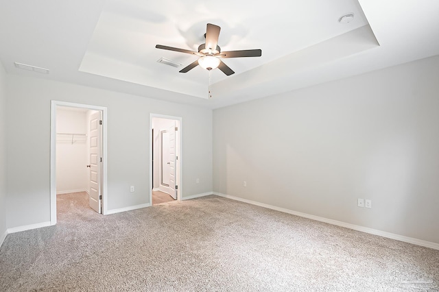 7929 Huntington Creek Ln, Pensacola, FL 32526 - unfurnished bedroom featuring a tray ceiling, a walk in closet, light colored carpet, a closet, and baseboards