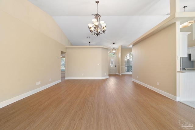 unfurnished living room with wood-type flooring, a wealth of natural light, and a chandelier