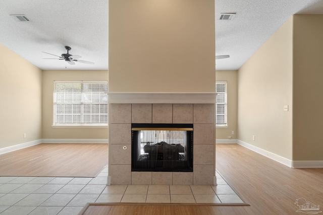 room details featuring ceiling fan, hardwood / wood-style floors, a tile fireplace, and a textured ceiling