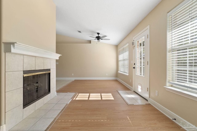 unfurnished living room featuring ceiling fan, a fireplace, light hardwood / wood-style floors, a textured ceiling, and vaulted ceiling