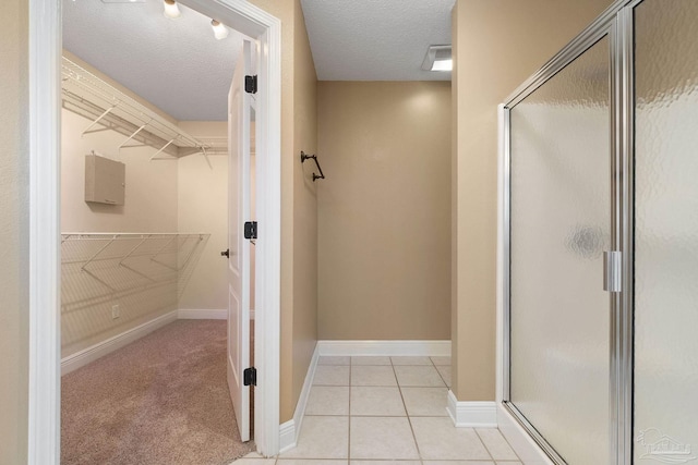 bathroom with walk in shower, tile patterned flooring, and a textured ceiling