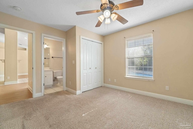 unfurnished bedroom with ceiling fan, light colored carpet, a textured ceiling, and a closet