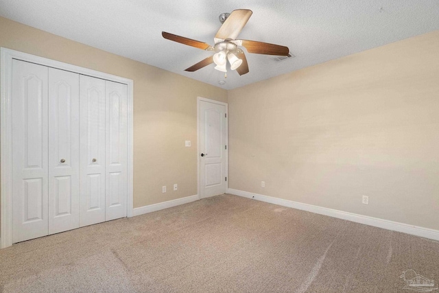 unfurnished bedroom with a textured ceiling, a closet, ceiling fan, and carpet