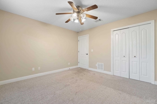 unfurnished bedroom with a textured ceiling, a closet, ceiling fan, and carpet flooring