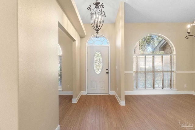 entrance foyer with an inviting chandelier, a wealth of natural light, and light wood-type flooring