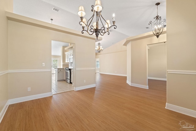 unfurnished dining area featuring lofted ceiling, light wood-type flooring, and a chandelier