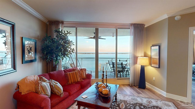 living area featuring baseboards, a water view, wood finished floors, and crown molding