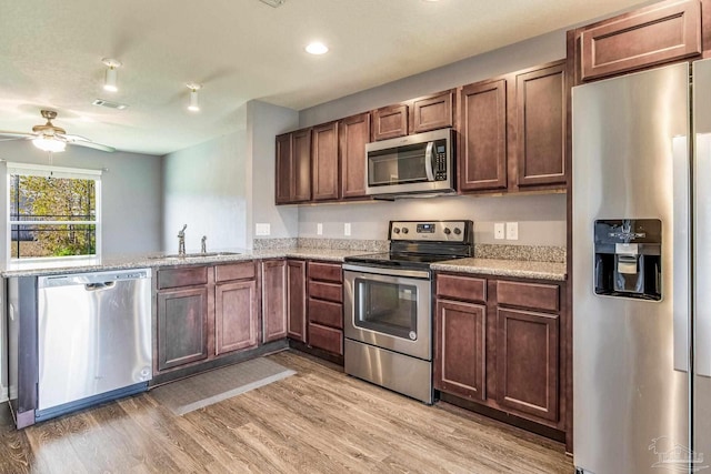 kitchen with ceiling fan, sink, light wood-type flooring, and stainless steel appliances