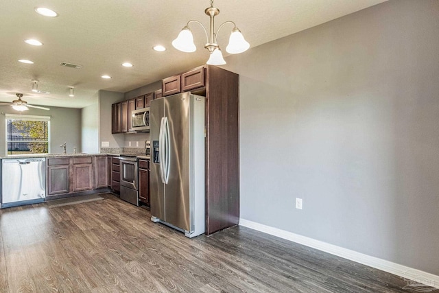 kitchen featuring pendant lighting, dark hardwood / wood-style floors, ceiling fan with notable chandelier, and appliances with stainless steel finishes