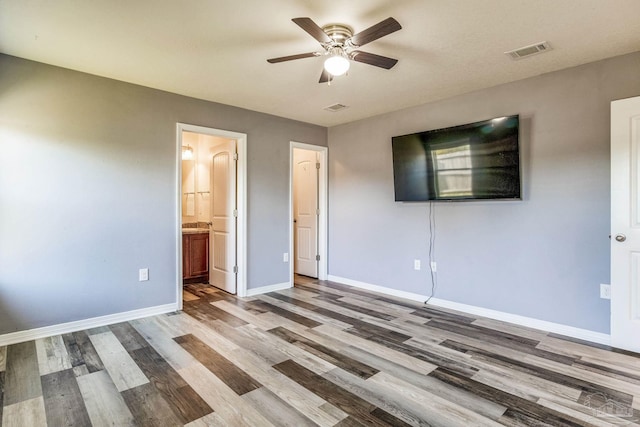 unfurnished bedroom with hardwood / wood-style flooring, ceiling fan, and ensuite bath