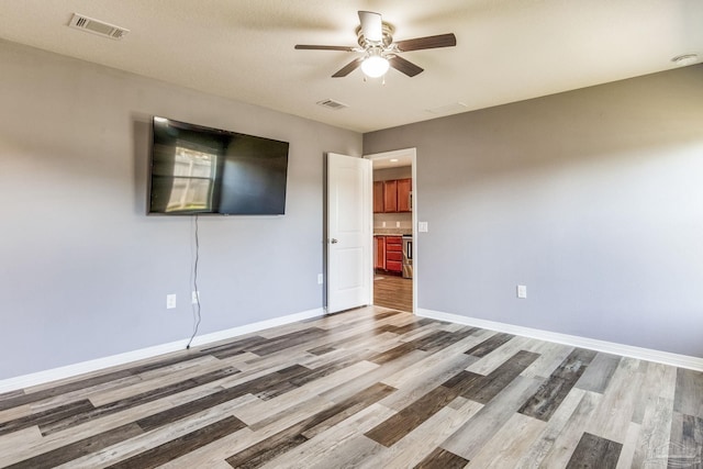 unfurnished room with ceiling fan, light wood-type flooring, and a textured ceiling