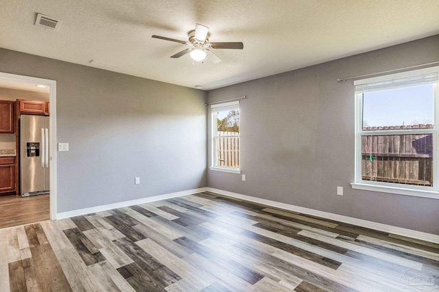 empty room with ceiling fan, light hardwood / wood-style floors, and a textured ceiling