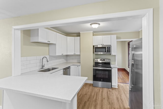 kitchen featuring kitchen peninsula, appliances with stainless steel finishes, white cabinets, and sink