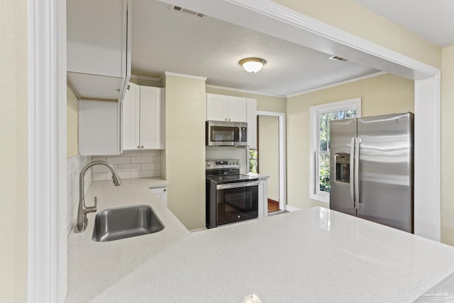 kitchen featuring white cabinetry, sink, tasteful backsplash, kitchen peninsula, and appliances with stainless steel finishes