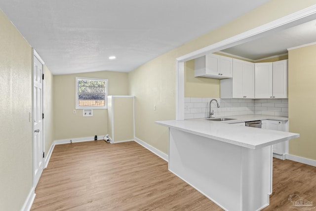 kitchen with light hardwood / wood-style floors, white cabinetry, lofted ceiling, and sink