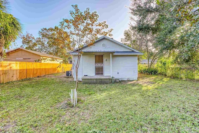 back of house featuring a lawn and central air condition unit