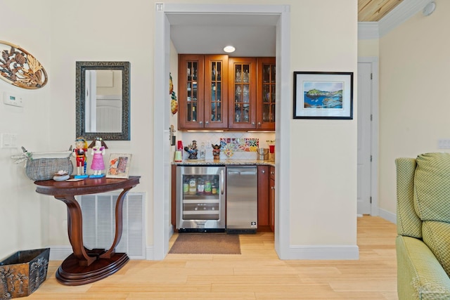 bar with decorative backsplash, light wood-type flooring, fridge, and beverage cooler