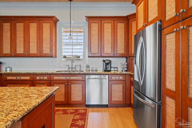 kitchen with pendant lighting, sink, light stone countertops, appliances with stainless steel finishes, and tasteful backsplash