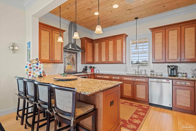 kitchen with light stone counters, stainless steel appliances, sink, wall chimney range hood, and a breakfast bar area