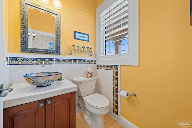 bathroom featuring hardwood / wood-style flooring, vanity, tile walls, and toilet