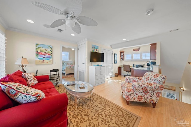 living room featuring light hardwood / wood-style flooring, ceiling fan, and crown molding