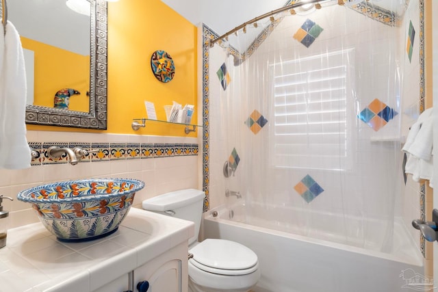 full bathroom with bathtub / shower combination, vanity, toilet, and tile walls