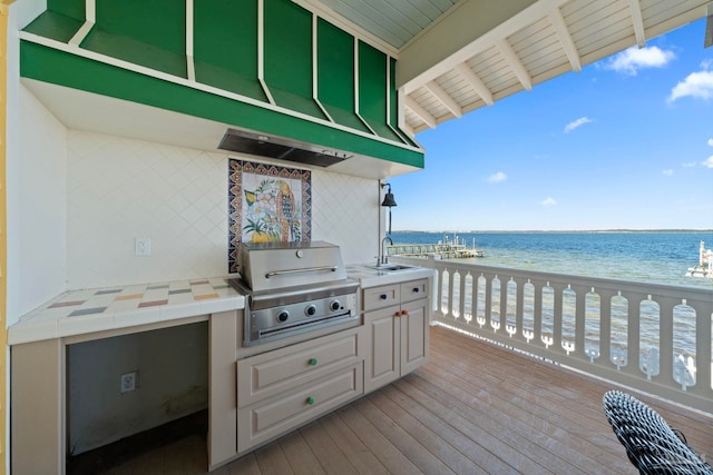 wooden terrace with sink, a view of the beach, exterior kitchen, a water view, and a grill