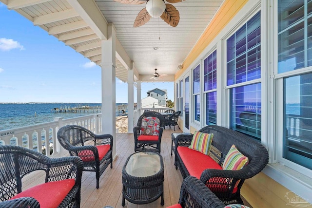 balcony featuring outdoor lounge area, ceiling fan, a water view, and a view of the beach