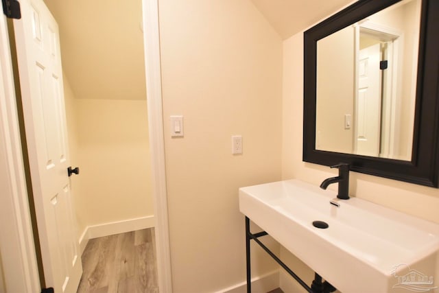 bathroom with lofted ceiling, sink, and hardwood / wood-style flooring