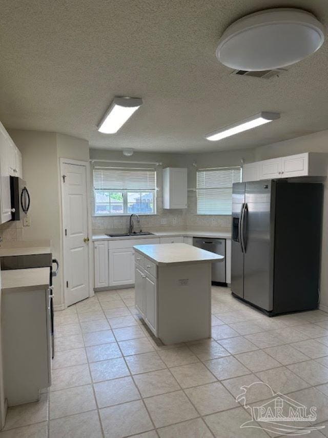 kitchen featuring white cabinets, light tile patterned floors, sink, a kitchen island, and stainless steel appliances