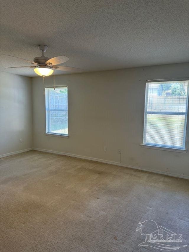 spare room featuring light colored carpet, ceiling fan, a textured ceiling, and baseboards