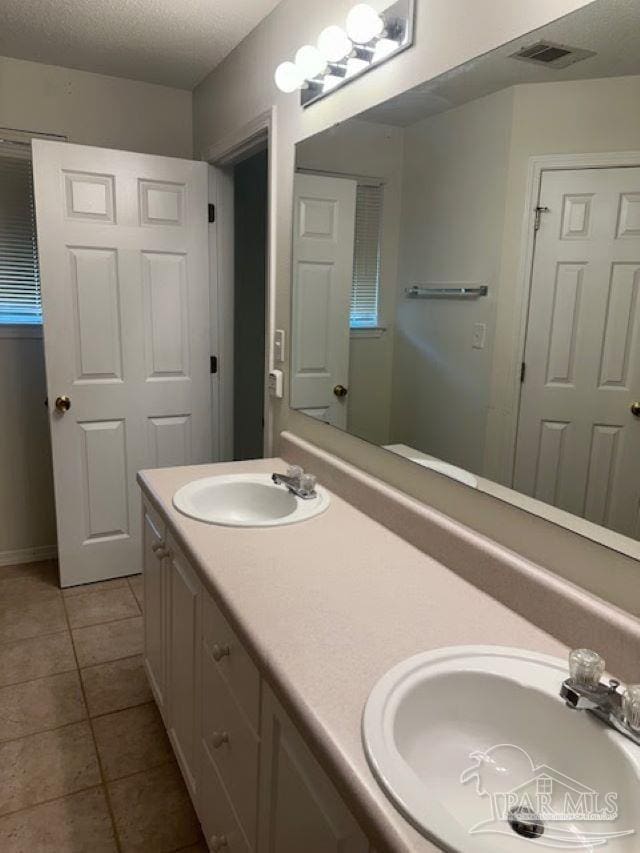 full bath with a textured ceiling, visible vents, a sink, and tile patterned floors