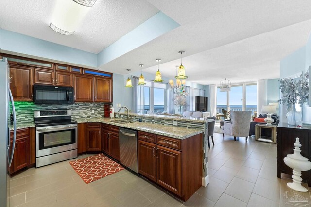 kitchen featuring light tile patterned floors, kitchen peninsula, stainless steel appliances, decorative backsplash, and a kitchen bar