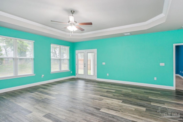 empty room with crown molding, dark hardwood / wood-style floors, and a raised ceiling