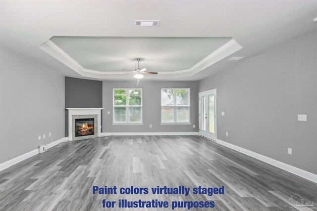 unfurnished living room with ceiling fan, wood-type flooring, and a tray ceiling