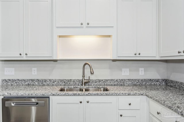 kitchen with stainless steel dishwasher, light stone countertops, sink, and white cabinets