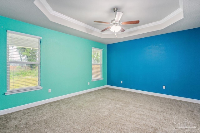 unfurnished room featuring ceiling fan, ornamental molding, a raised ceiling, and a healthy amount of sunlight