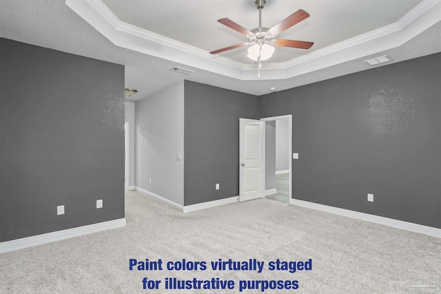 carpeted empty room featuring ornamental molding, ceiling fan, and a tray ceiling