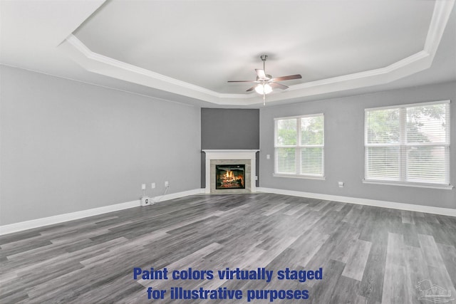 unfurnished living room featuring hardwood / wood-style floors, a fireplace, ornamental molding, ceiling fan, and a tray ceiling