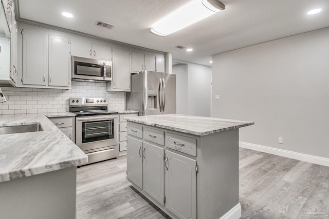 kitchen featuring gray cabinets, a center island, light hardwood / wood-style floors, and stainless steel appliances