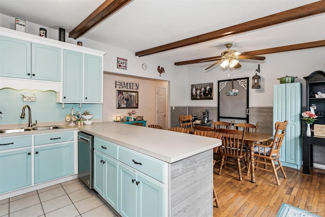 kitchen with blue cabinetry, beamed ceiling, ceiling fan, a sink, and a peninsula