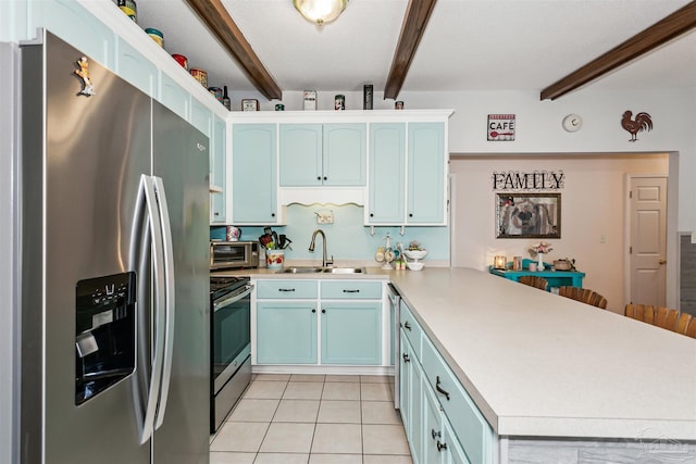 kitchen featuring beamed ceiling, a sink, a peninsula, light countertops, and appliances with stainless steel finishes