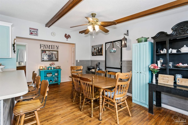 dining room featuring ceiling fan, hardwood / wood-style floors, and beamed ceiling